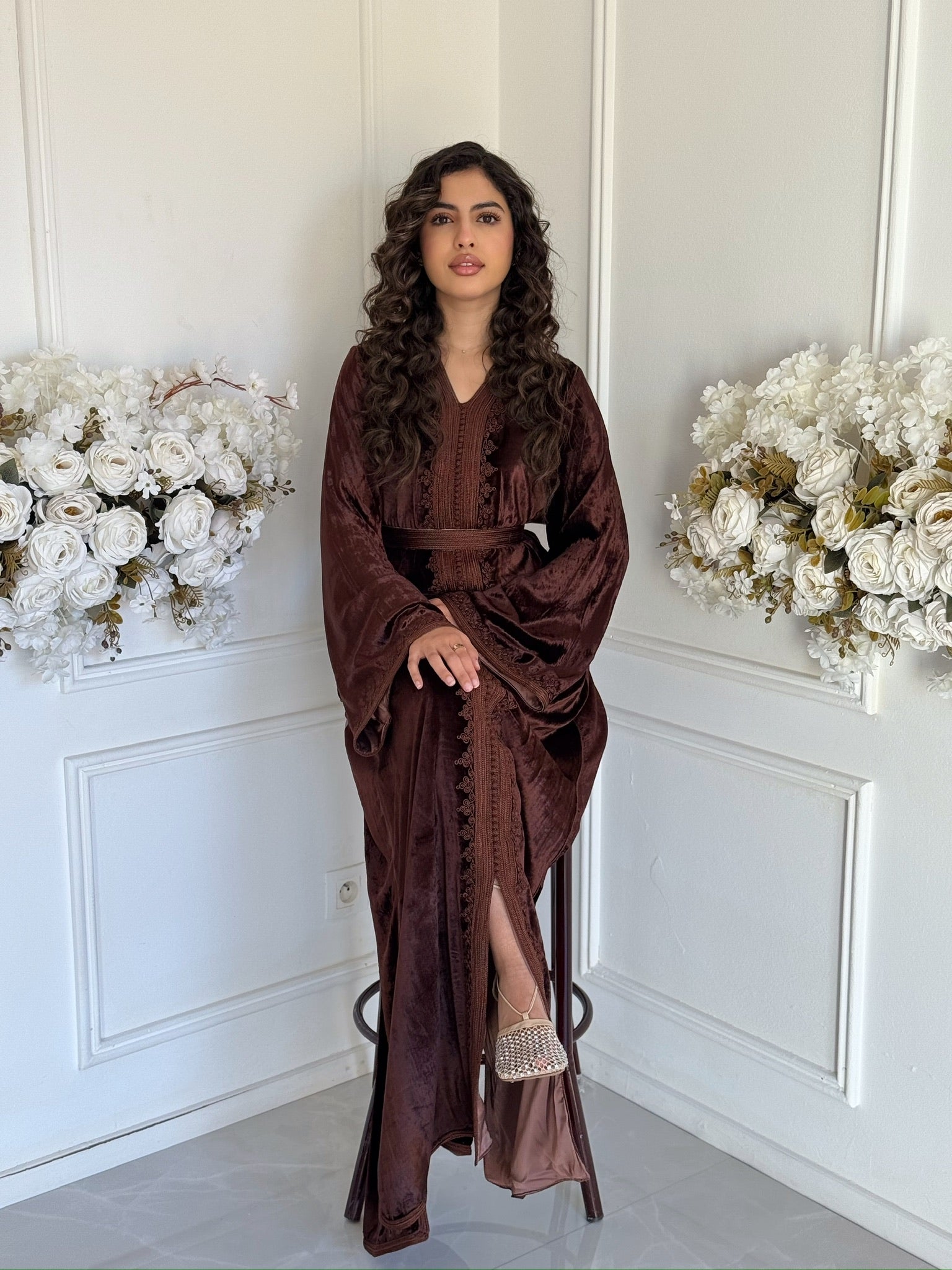 Full view of the brown velvet Caftan Farah featuring embroidered details in a refined setting.